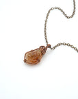 Close up of wire wrapped raw citrine crystal showing antique bronze copper craftsmanship and natural stone texture