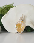 Back angle look at simple raw citrine pendant with silver wire wrapping
