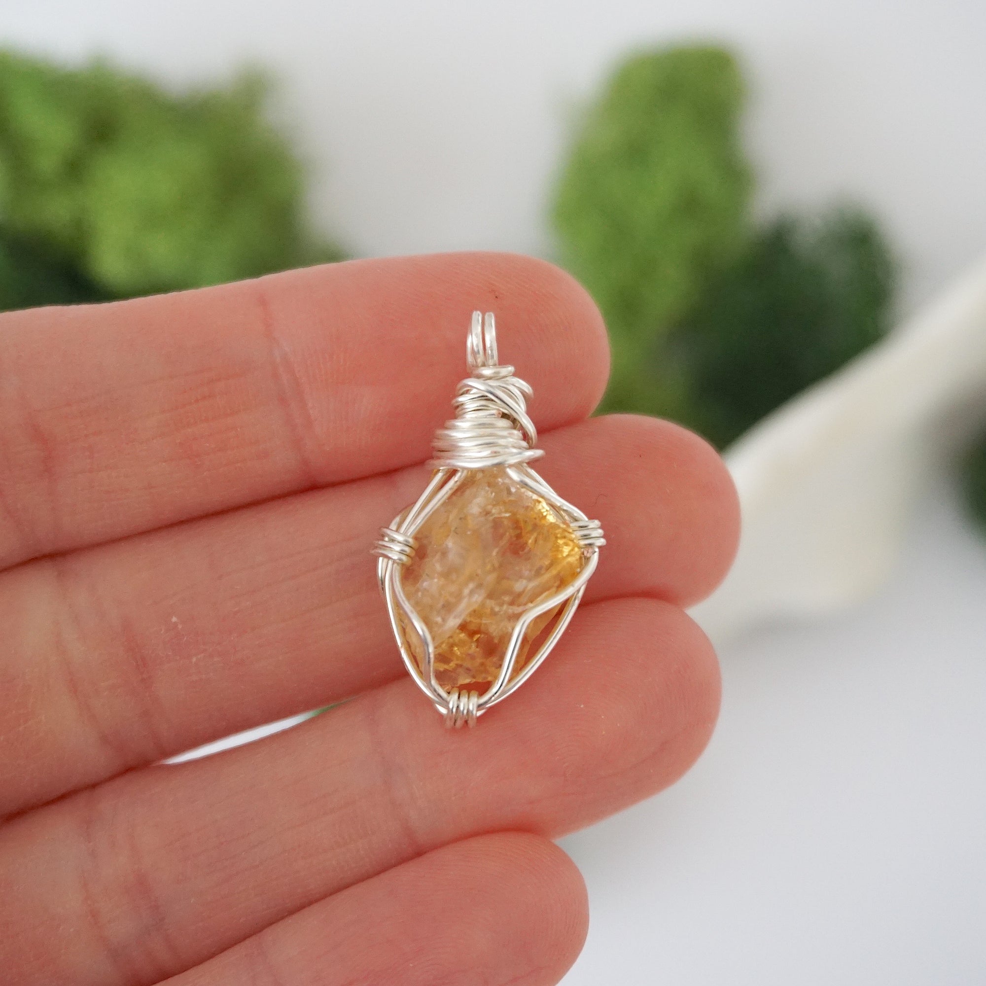 Simple raw citrine pendant shown in hand for size reference
