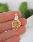 Simple raw citrine pendant shown in hand for size reference