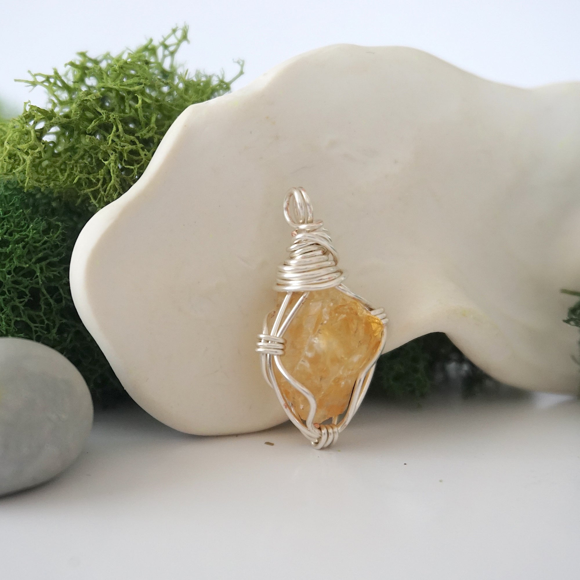 Detailed side angle view of simple raw citrine pendant in silver wire