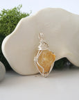 Detailed side angle view of simple raw citrine pendant in silver wire