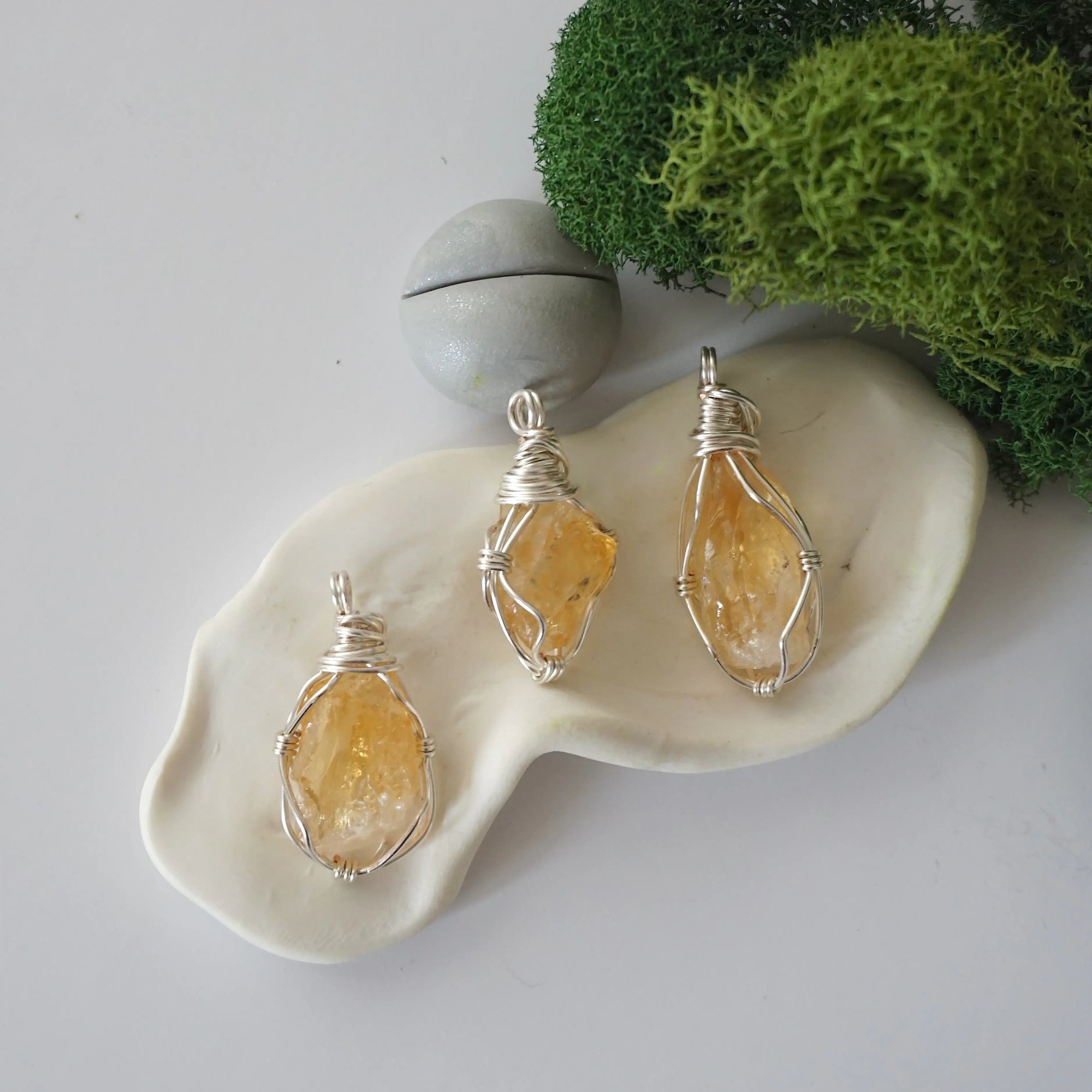 Three different raw citrine pendants displayed for variation reference