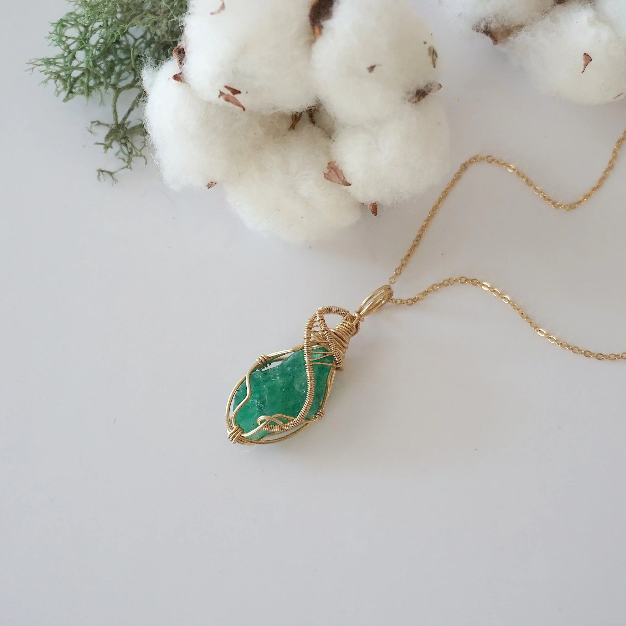 Raw emerald necklace in 14k gold filled laying flat. Handcrafted May birthstone jewelry for women by Designs by Nature Gems.