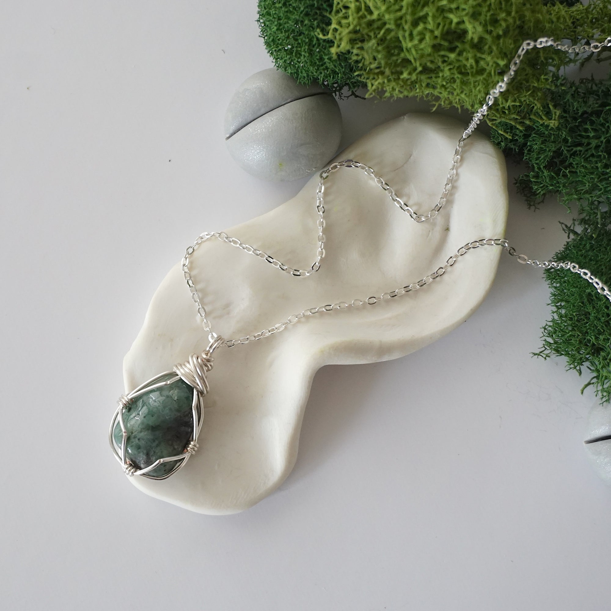 Simple raw emerald necklace with silver plated brass chain laying flat