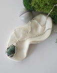 Simple raw emerald necklace with silver plated brass chain laying flat