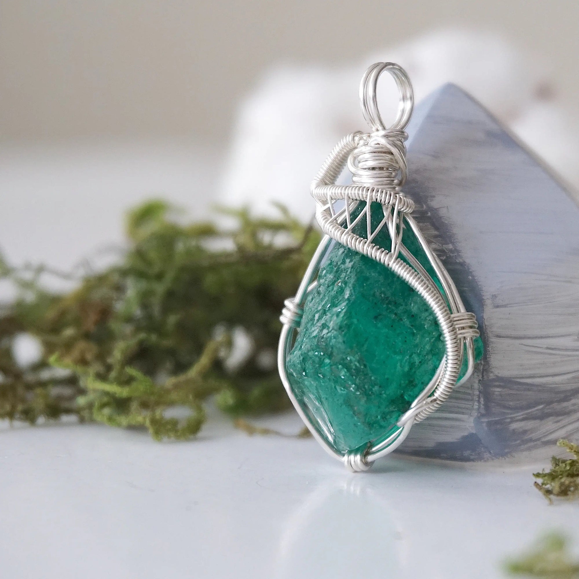 Left angle view of emerald necklace for women with natural raw emerald and detailed sterling silver wire wrapping