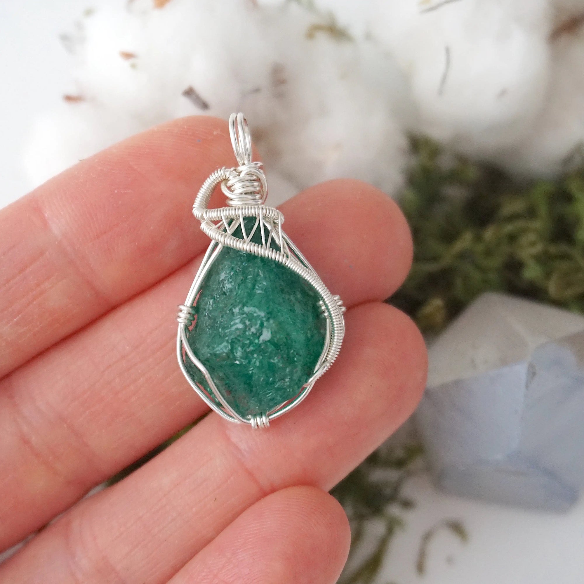 Raw emerald necklace for women shown in hand for size reference with natural emerald pendant in 925 sterling silver wire wrapping