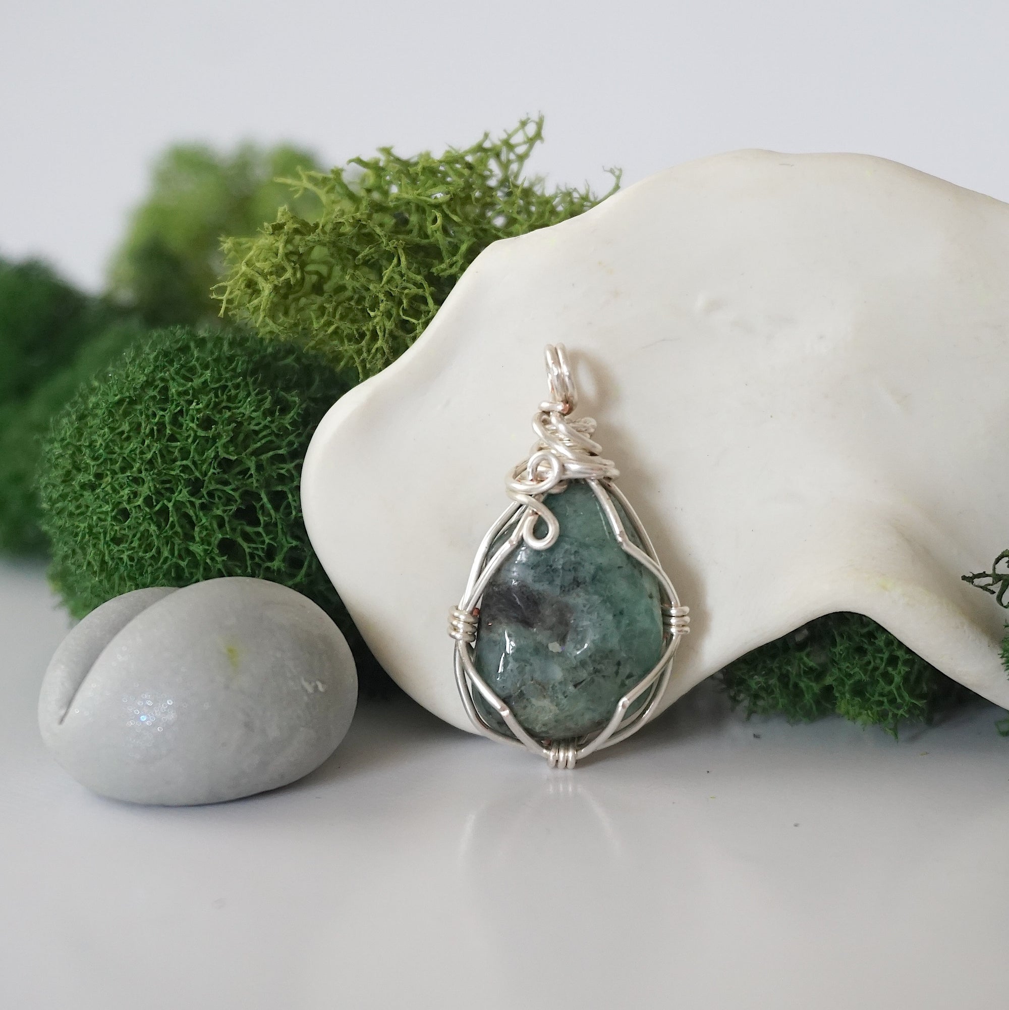 Back angle look at simple raw emerald pendant with silver wire wrapping