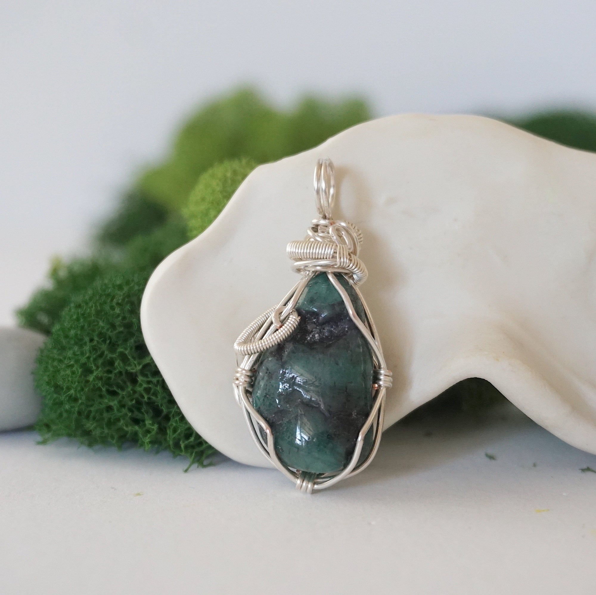 Back view of raw emerald pendant showing detailed artisan wire wrapping in soft silver copper.