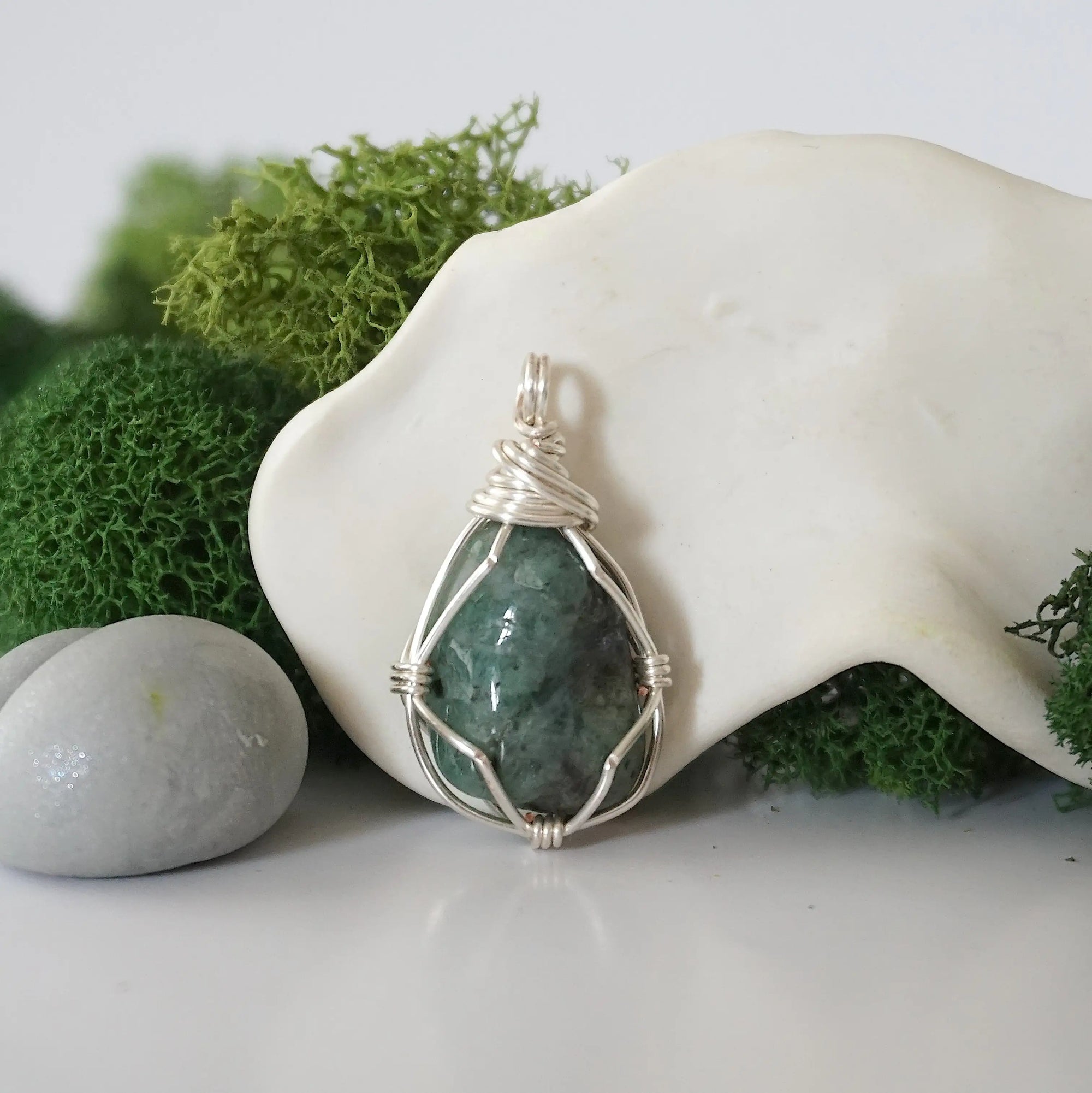 Detailed front angle view of simple raw emerald pendant in silver wire