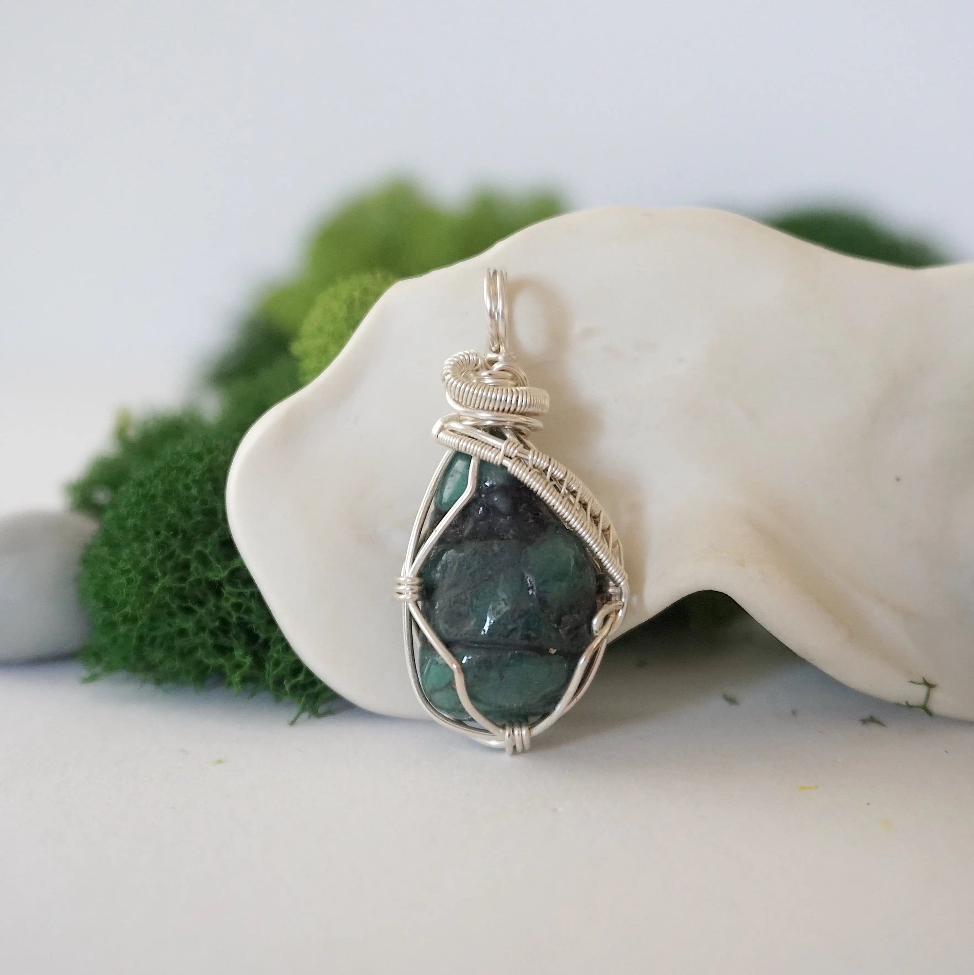 Front view of natural polished-raw emerald pendant with detailed artisan wire wrapping in soft silver copper.