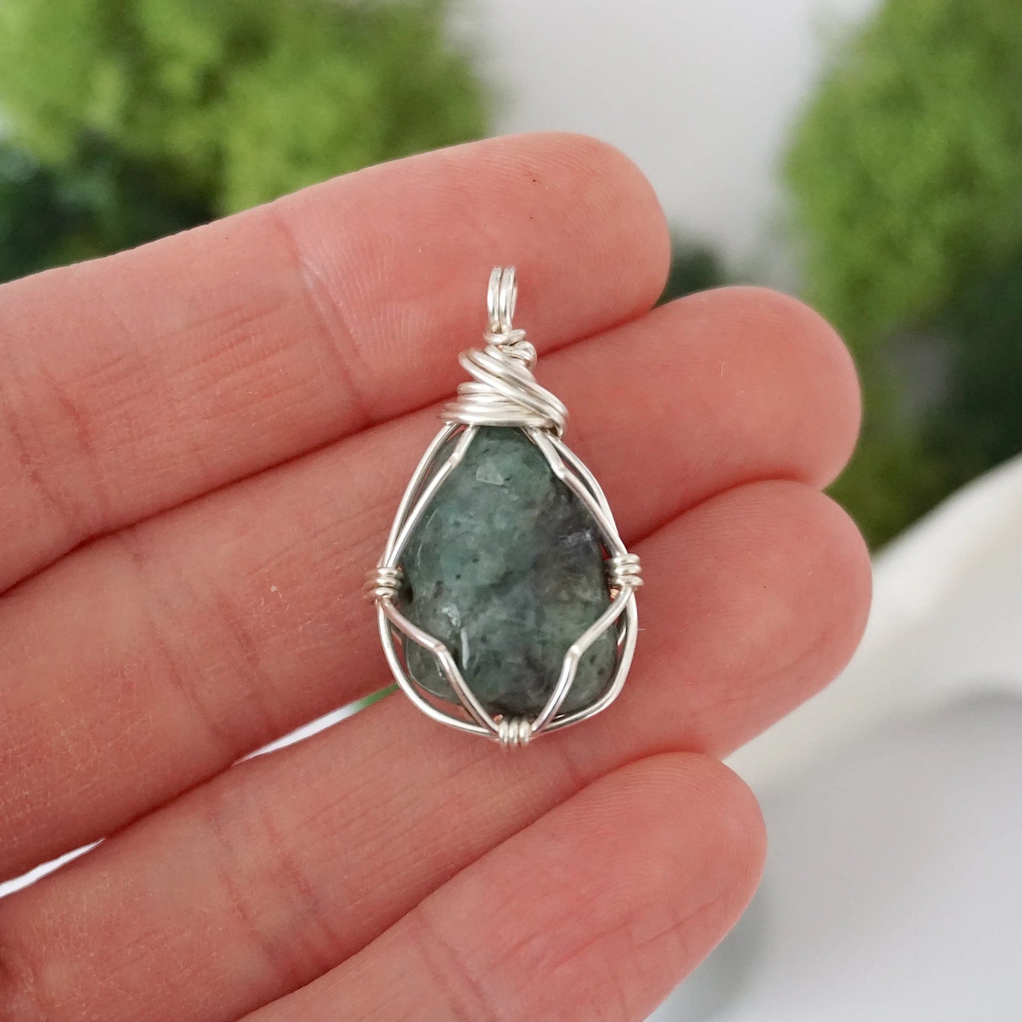 Simple raw emerald pendant shown in hand for size reference