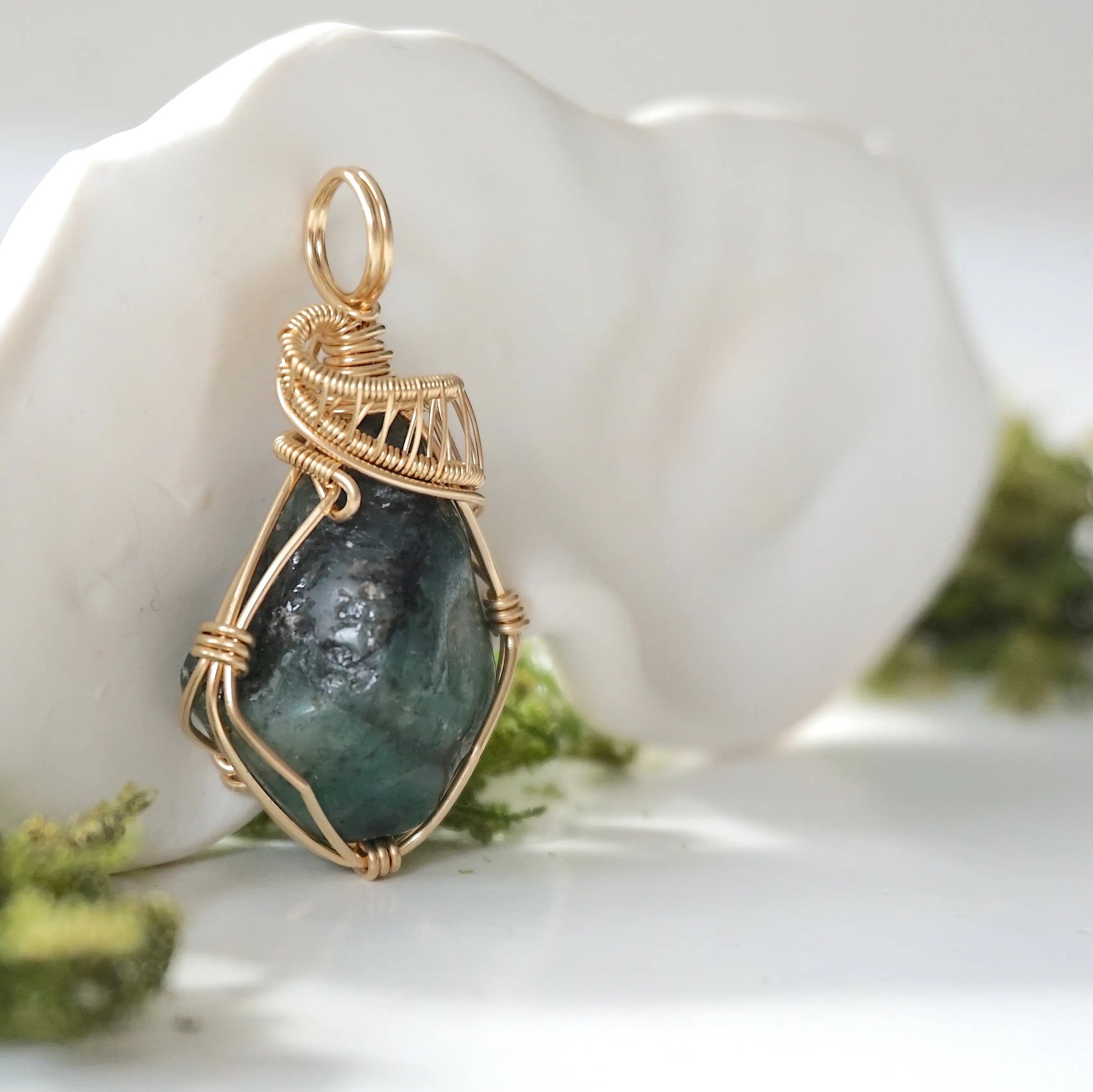 Right angle view of raw emerald pendant showing detailed handcrafted wire wrapping in 14k gold-filled wire.
