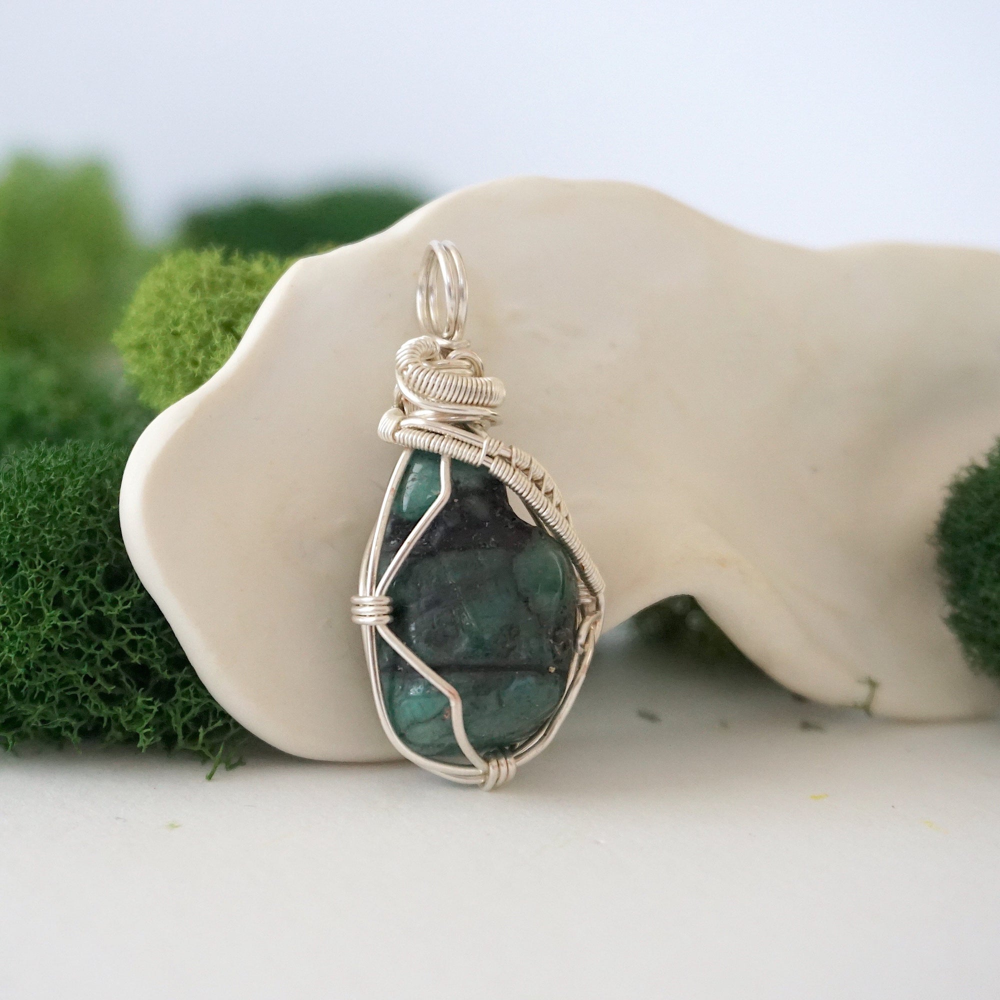 Right angle view of raw emerald pendant showing detailed handcrafted wire wrapping in soft silver copper.
