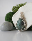 Detailed side angle view of simple raw emerald pendant in silver wire
