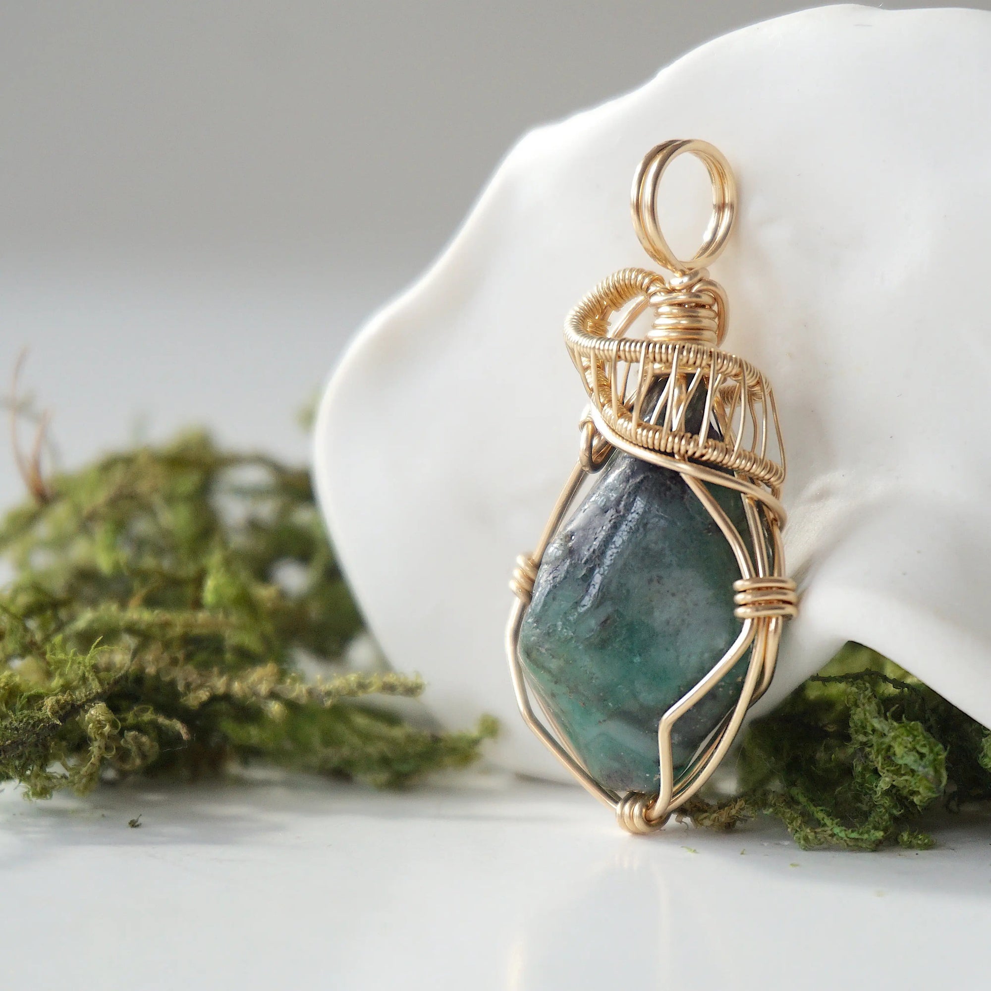 Side angle detail of natural emerald pendant highlighting intricate artisan wrapping in 14k gold-filled wire.