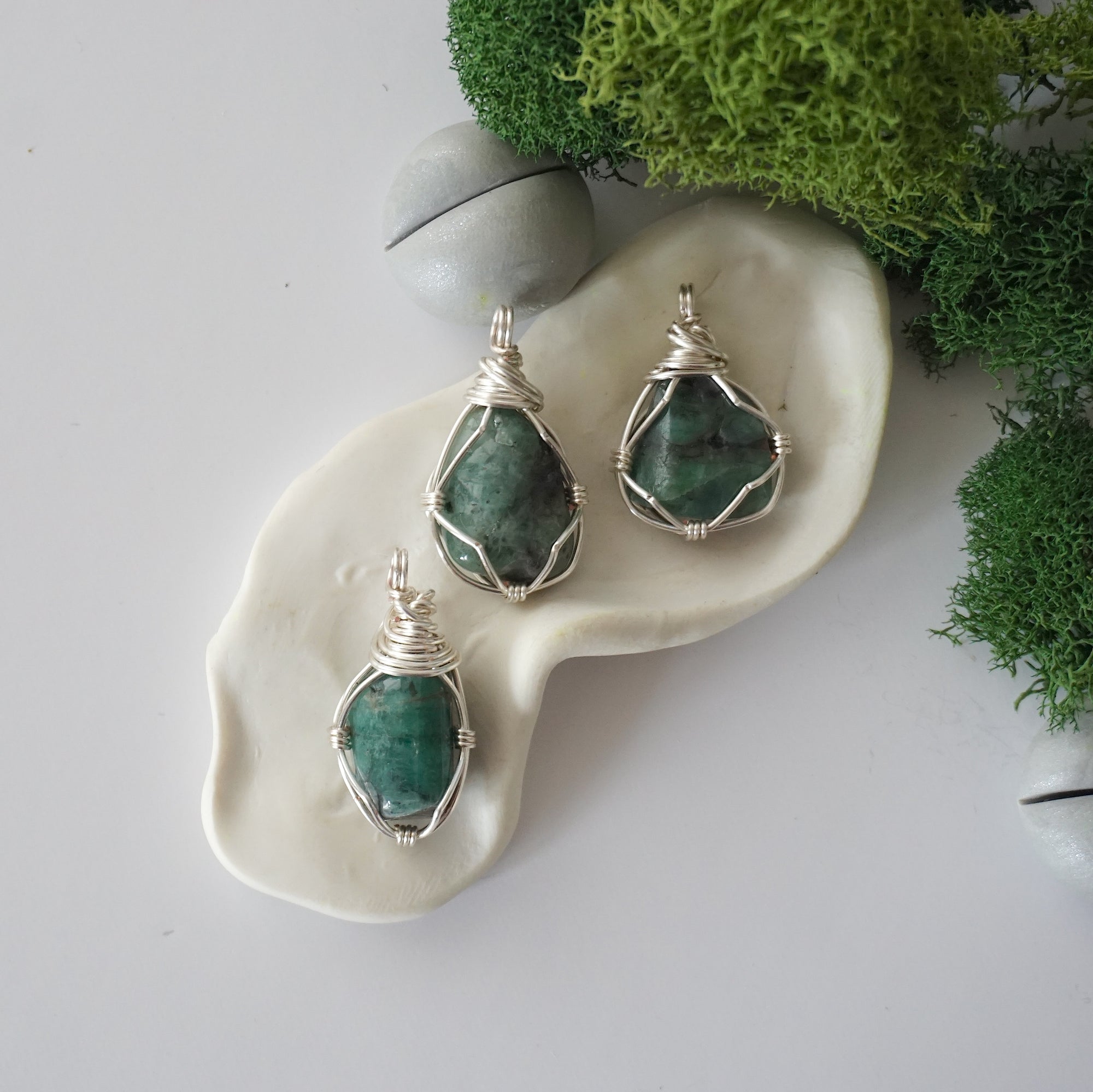 Three different raw emerald pendants displayed for variation reference