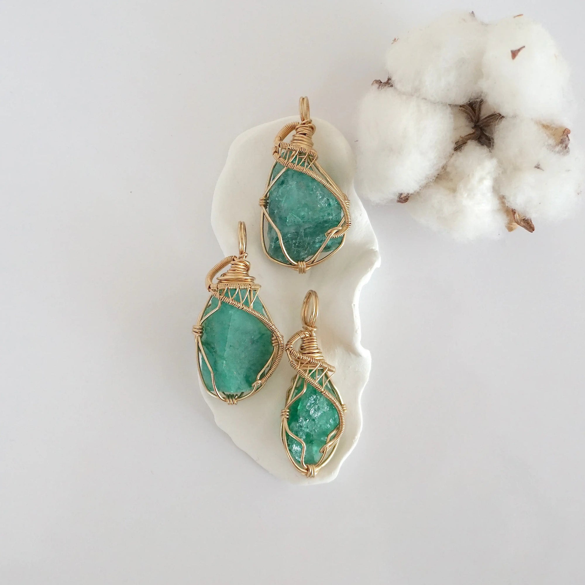 Three raw emerald pendants in 14k gold filled, showing natural variation in size, shape, and color. Handcrafted May birthstone jewelry by Designs by Nature Gems.