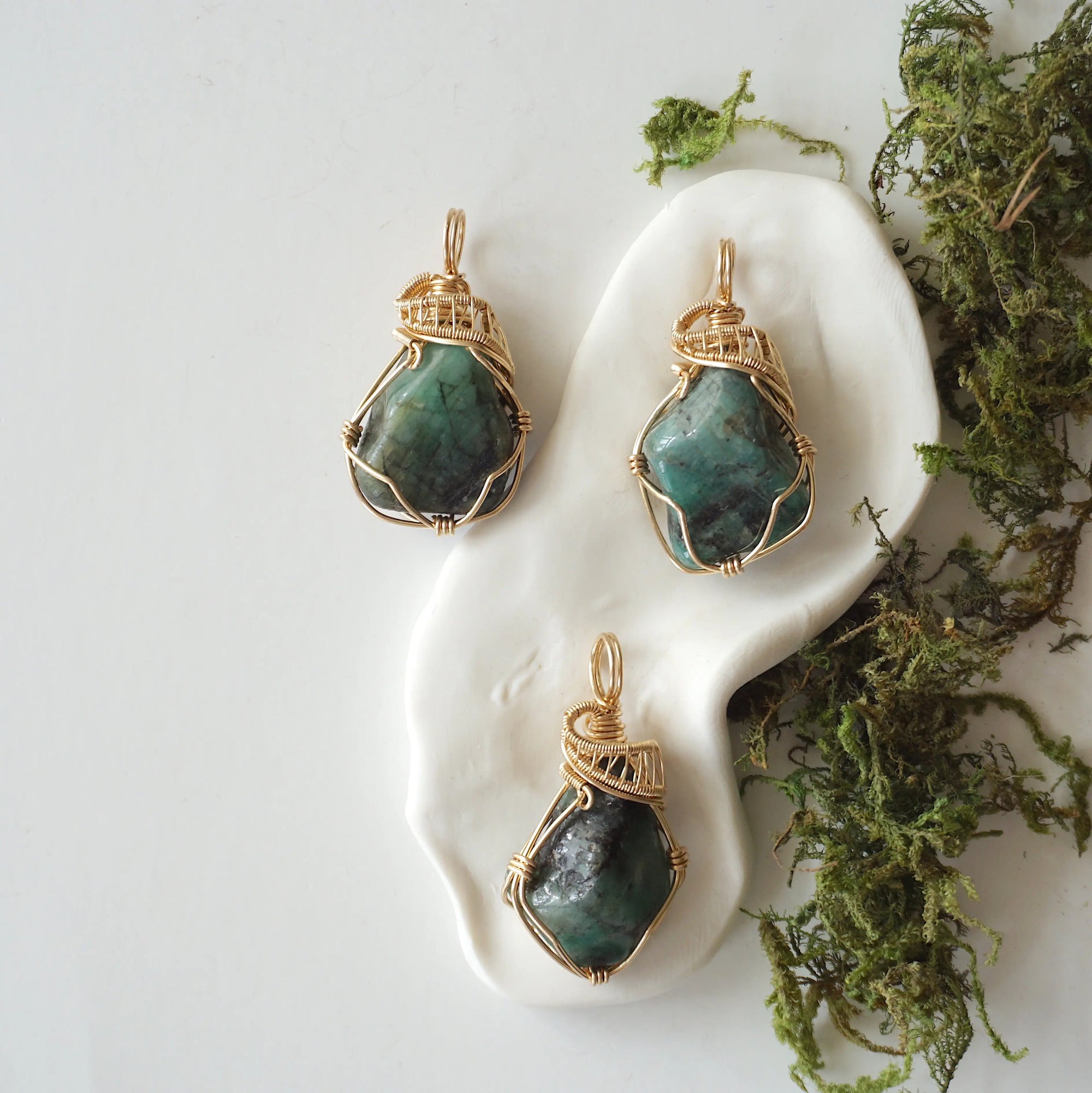 Three raw emerald pendants showing natural variation in size, shape, and green colour by Designs by Nature Gems.