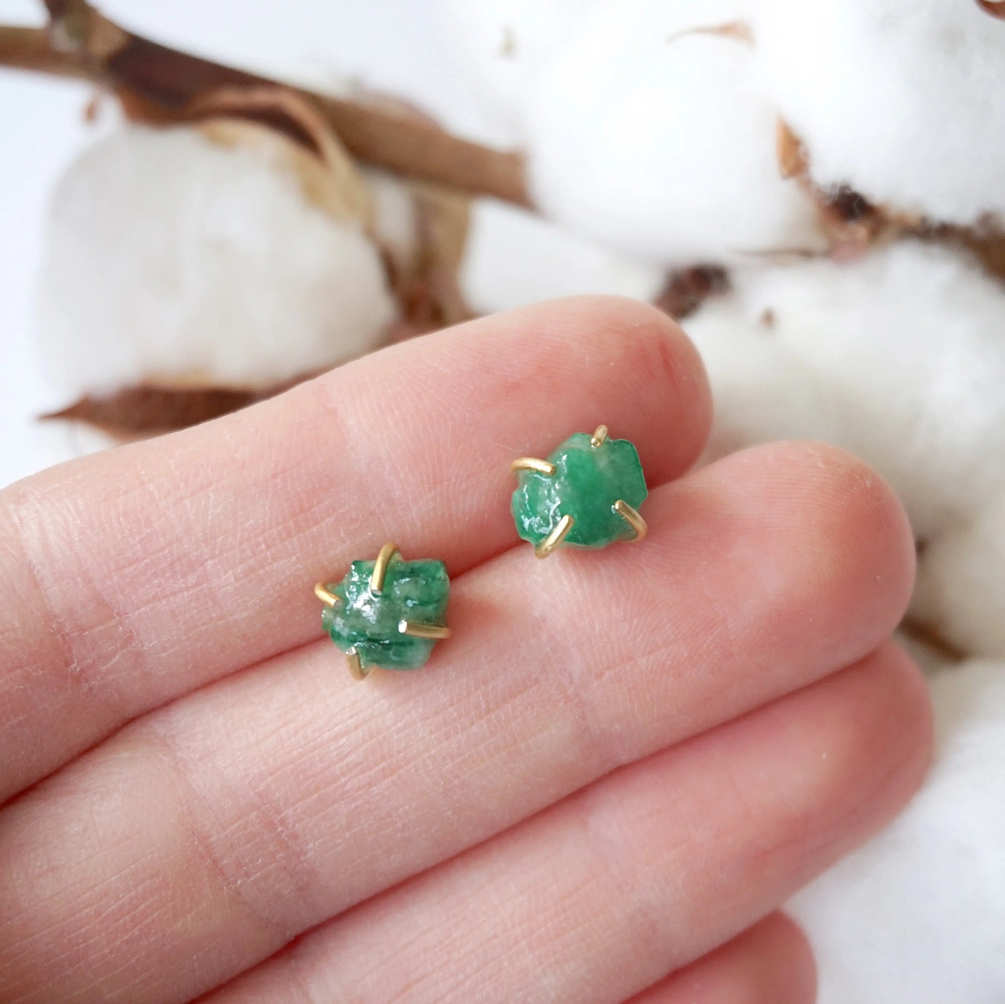 Natural raw emerald stud earrings in 14k gold vermeil shown in hand to display size and organic stone variation