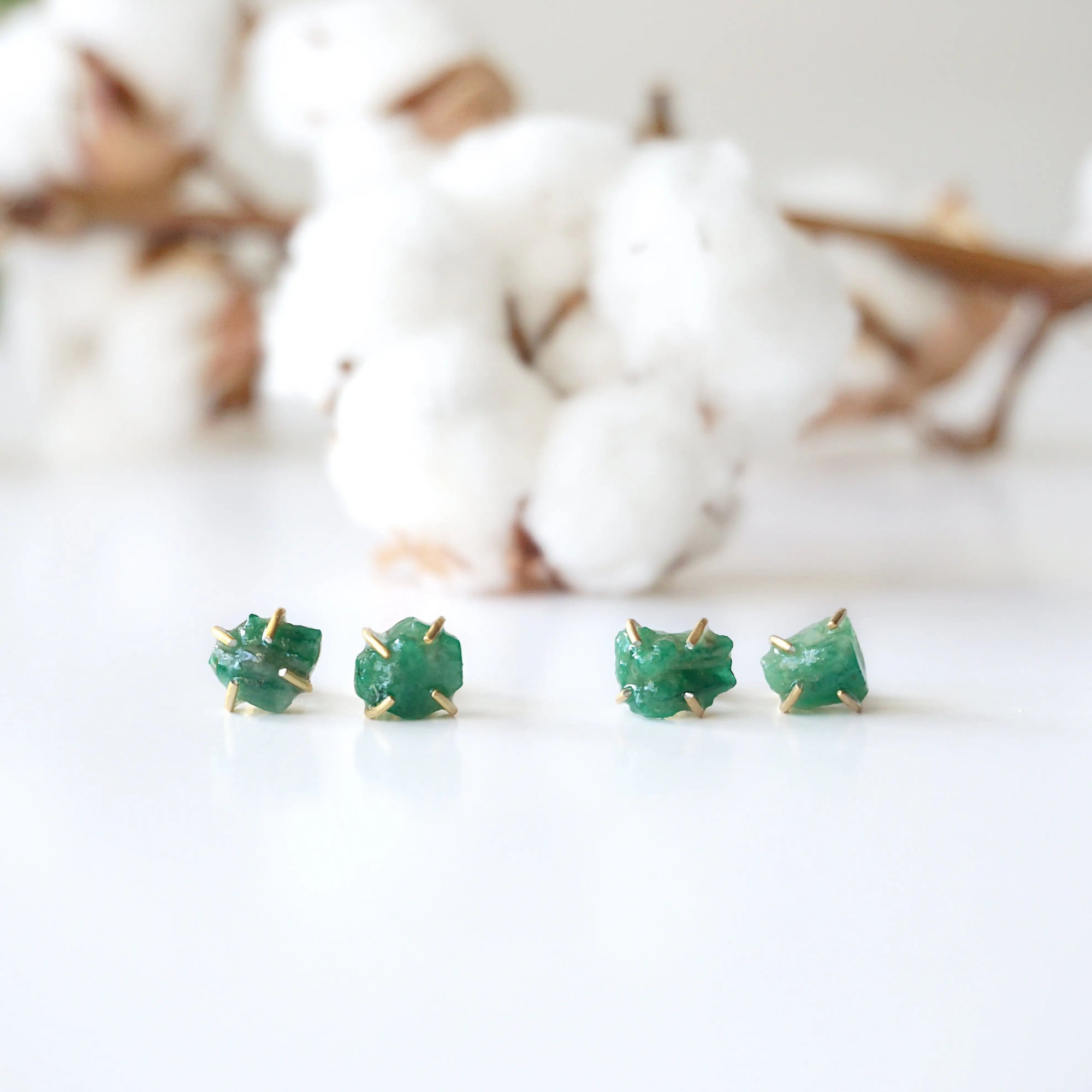 Two pairs of raw emerald stud earrings in 14k gold vermeil showing natural variation in emerald shape size and green colour