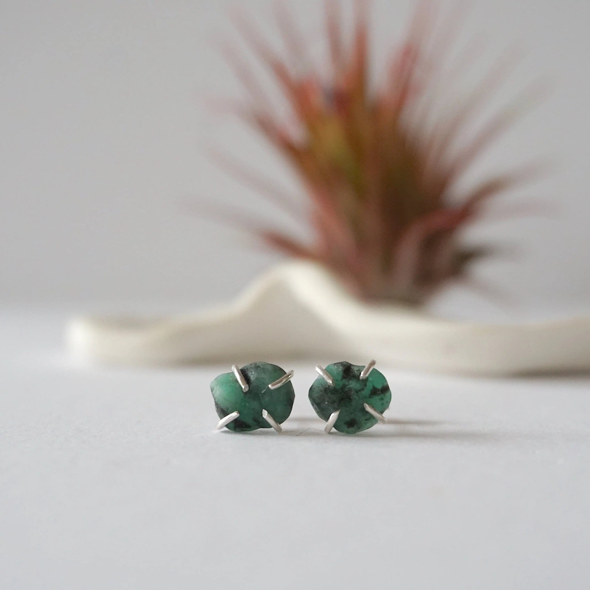 Front view of raw emerald stud earrings in sterling silver with natural emerald stones and handcrafted prong setting