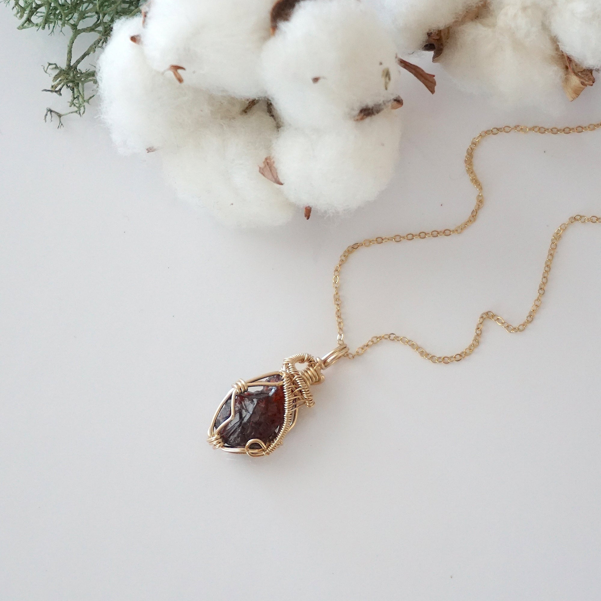 Raw garnet necklace in 14k gold filled laying flat. Handcrafted January birthstone jewelry for women by Designs by Nature Gems.