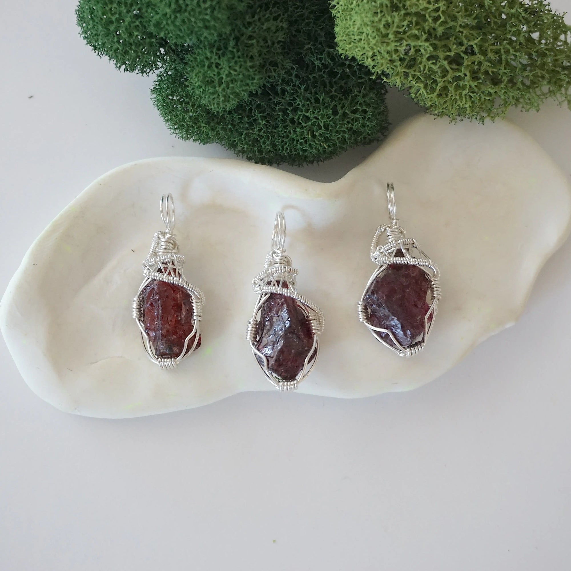 Three raw garnet necklaces showing natural crystal variations in handmade wire wrapped pendants