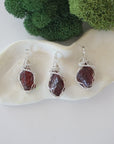 Three raw garnet necklaces showing natural crystal variations in handmade wire wrapped pendants