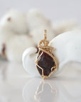 Detailed front view of raw garnet pendant in 14k gold filled. Unique wire wrapped January birthstone jewelry by Designs by Nature Gems.