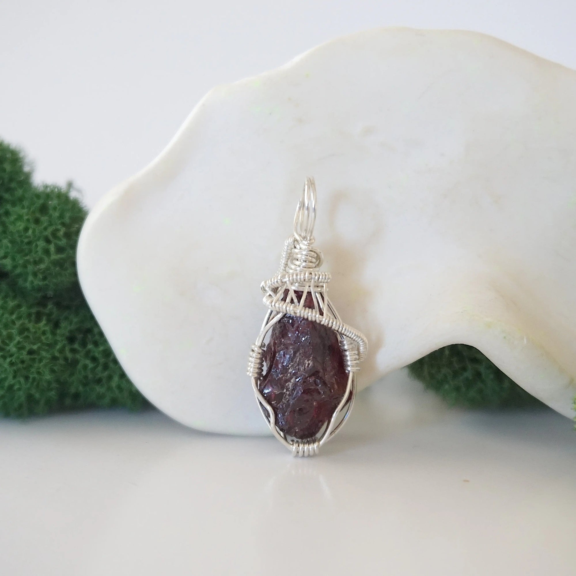 Close up front view of raw garnet crystal with detailed 925 sterling silver wire wrapping