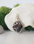 Back angle look at simple raw garnet pendant with silver wire wrapping