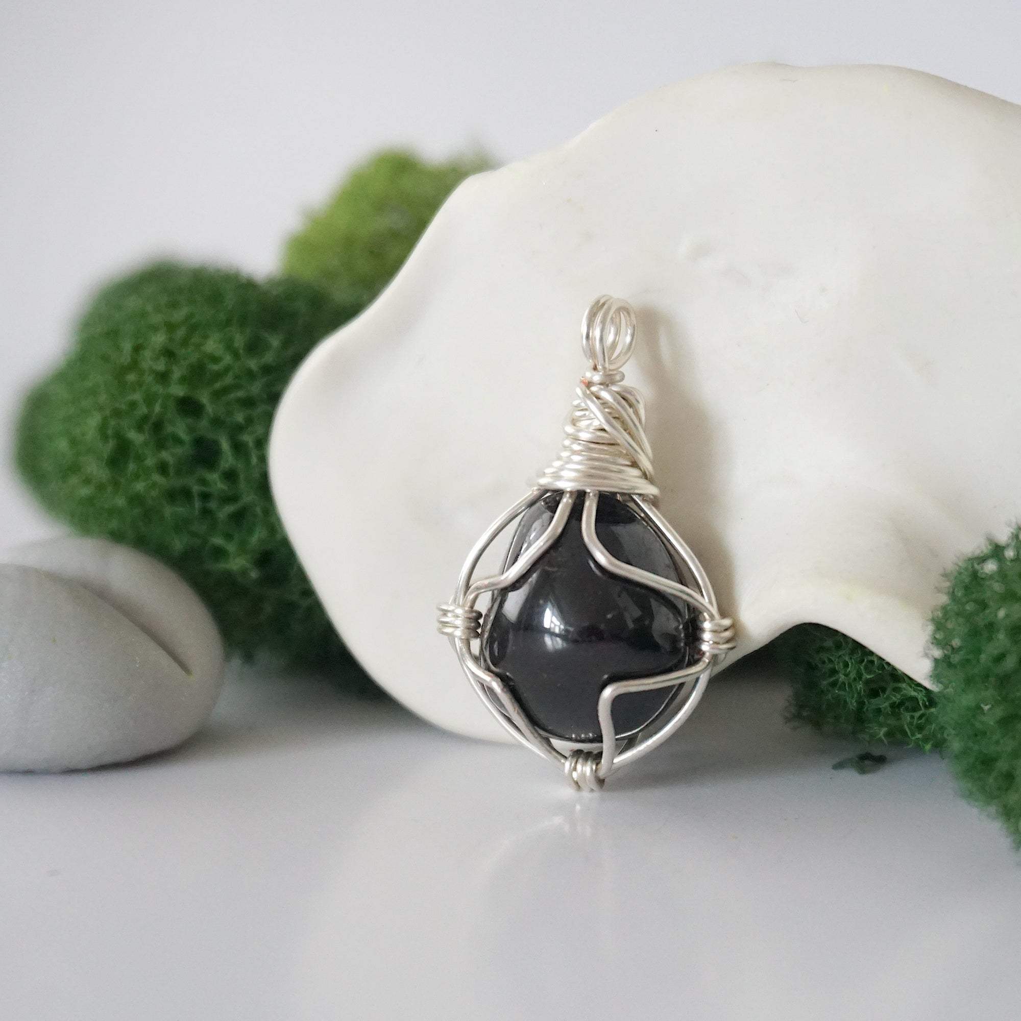 Detailed side angle view of simple raw garnet pendant in silver wire