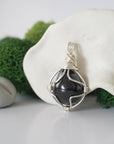 Detailed side angle view of simple raw garnet pendant in silver wire
