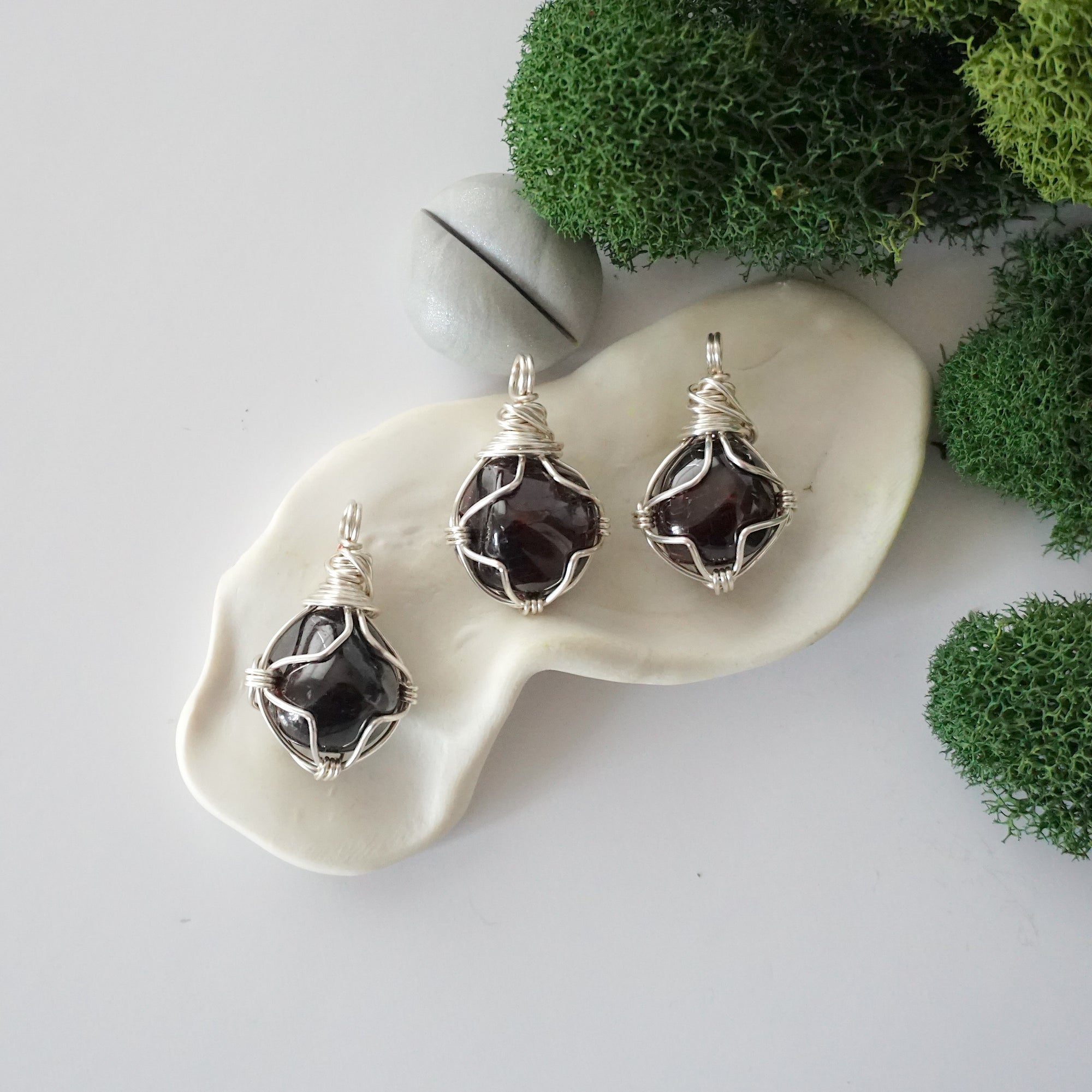 Three different raw garnet pendants displayed for variation reference