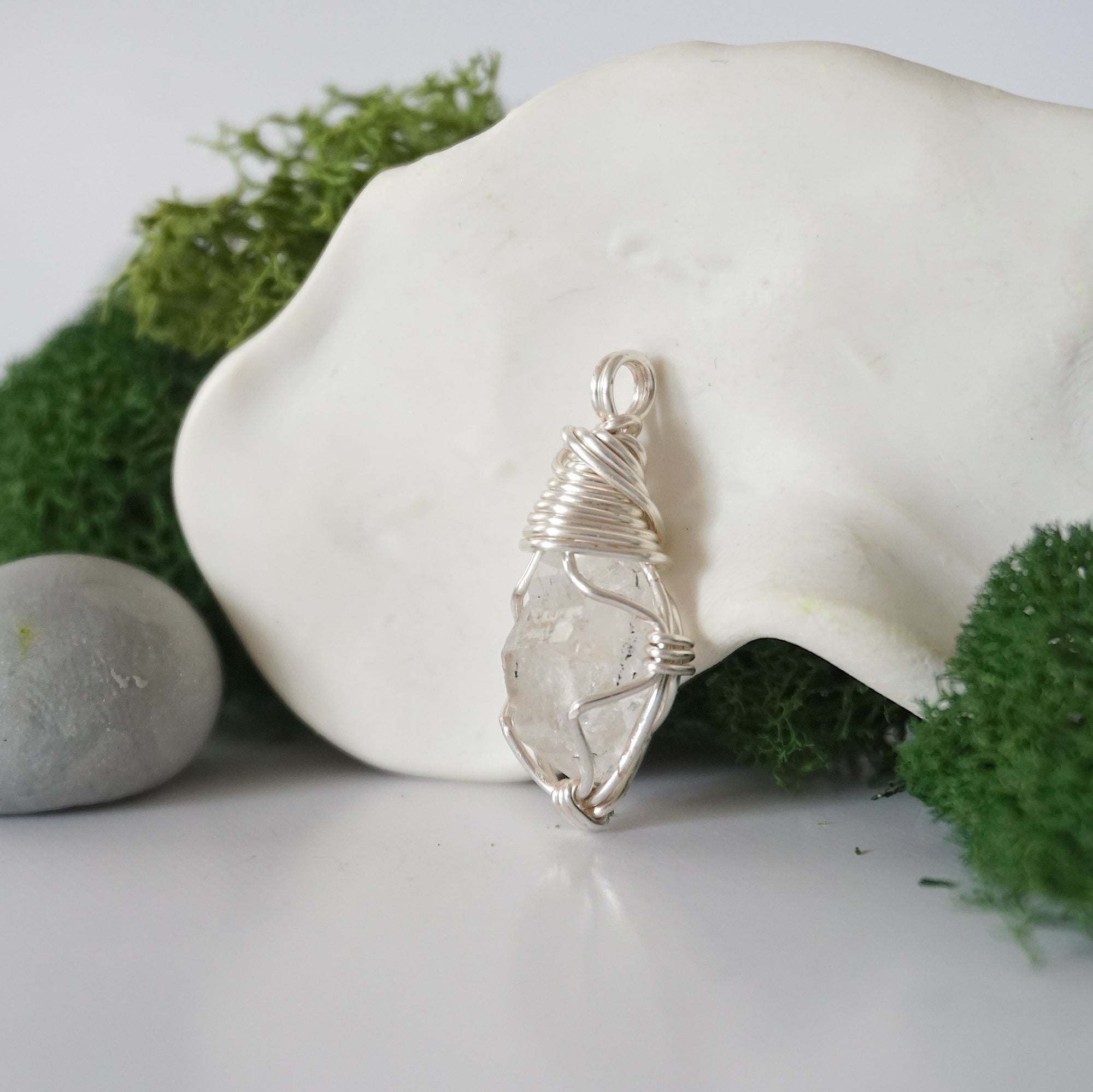 Detailed side angle view of simple raw Herkimer diamond pendant in silver wire