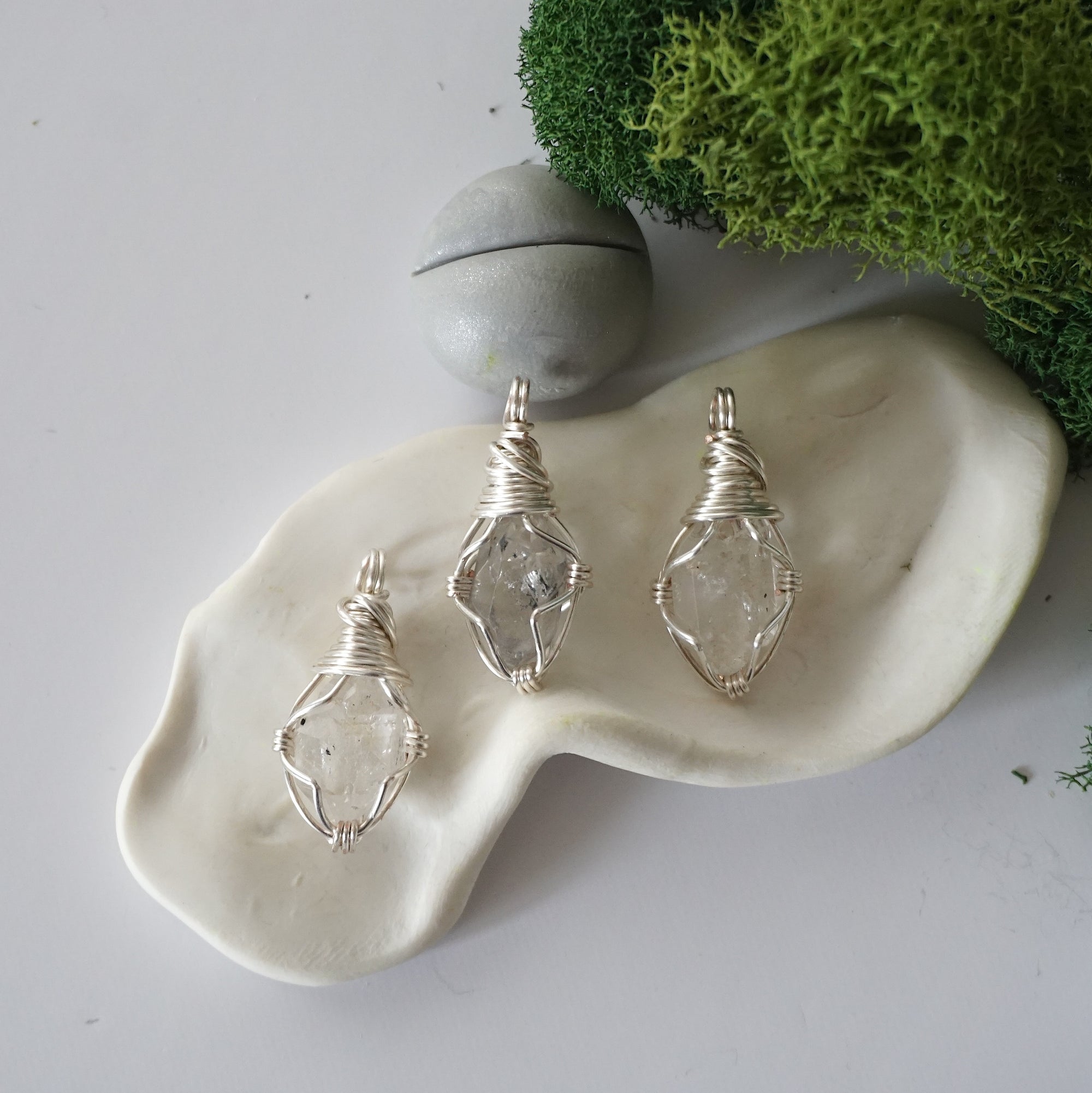 Three different raw Herkimer diamond pendants displayed for variation reference