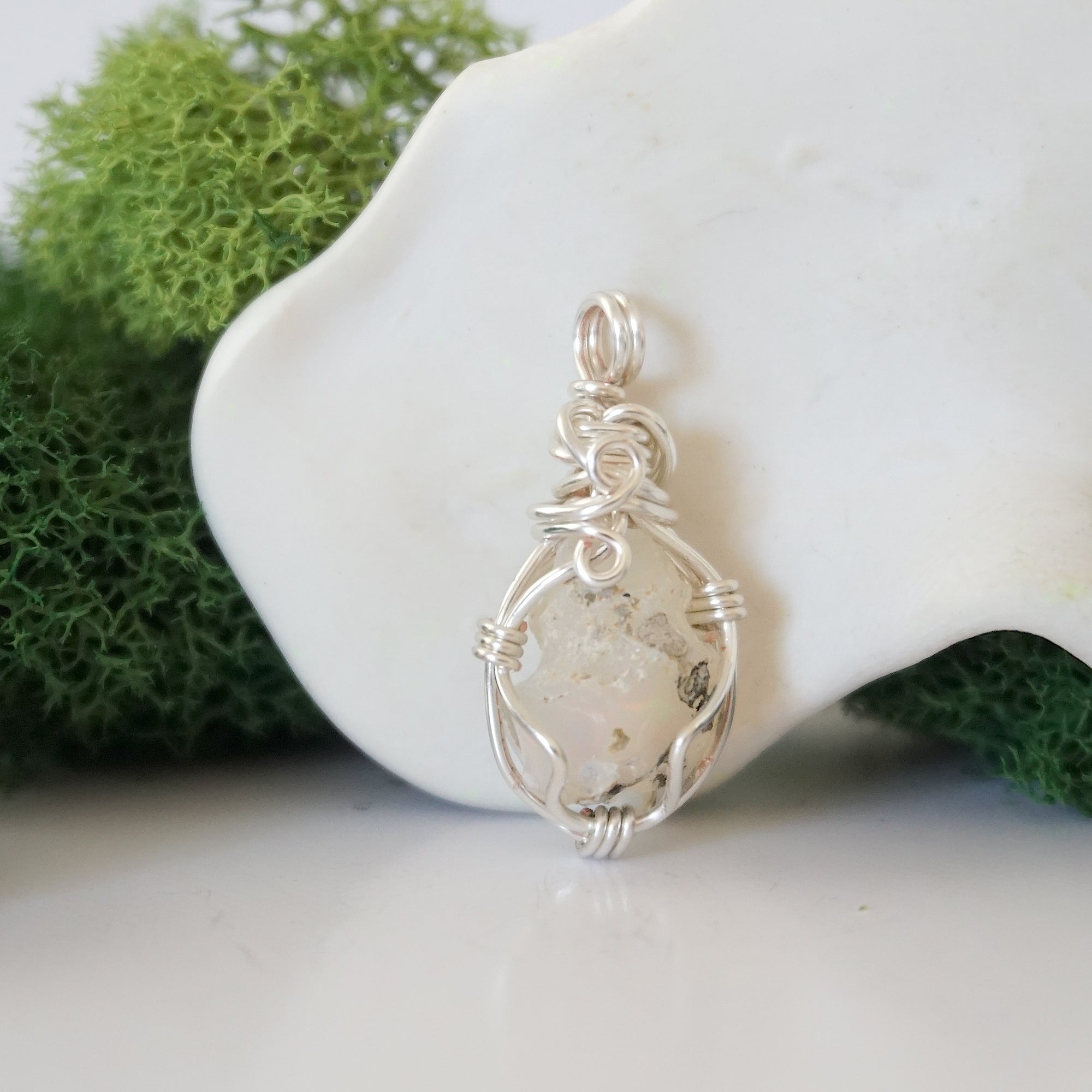 Back angle look at simple raw opal pendant with silver wire wrapping