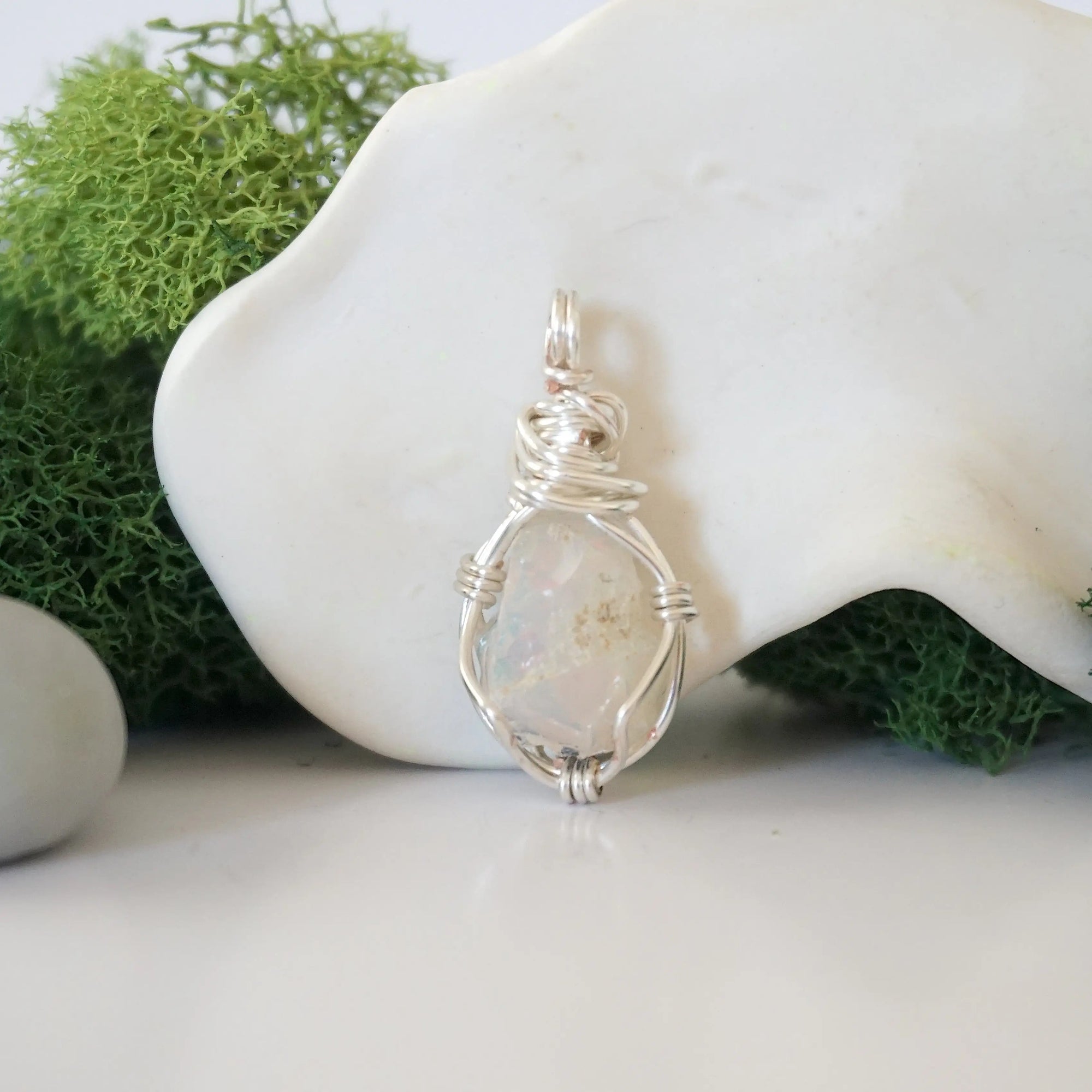 Detailed front angle view of simple raw opal pendant in silver wire