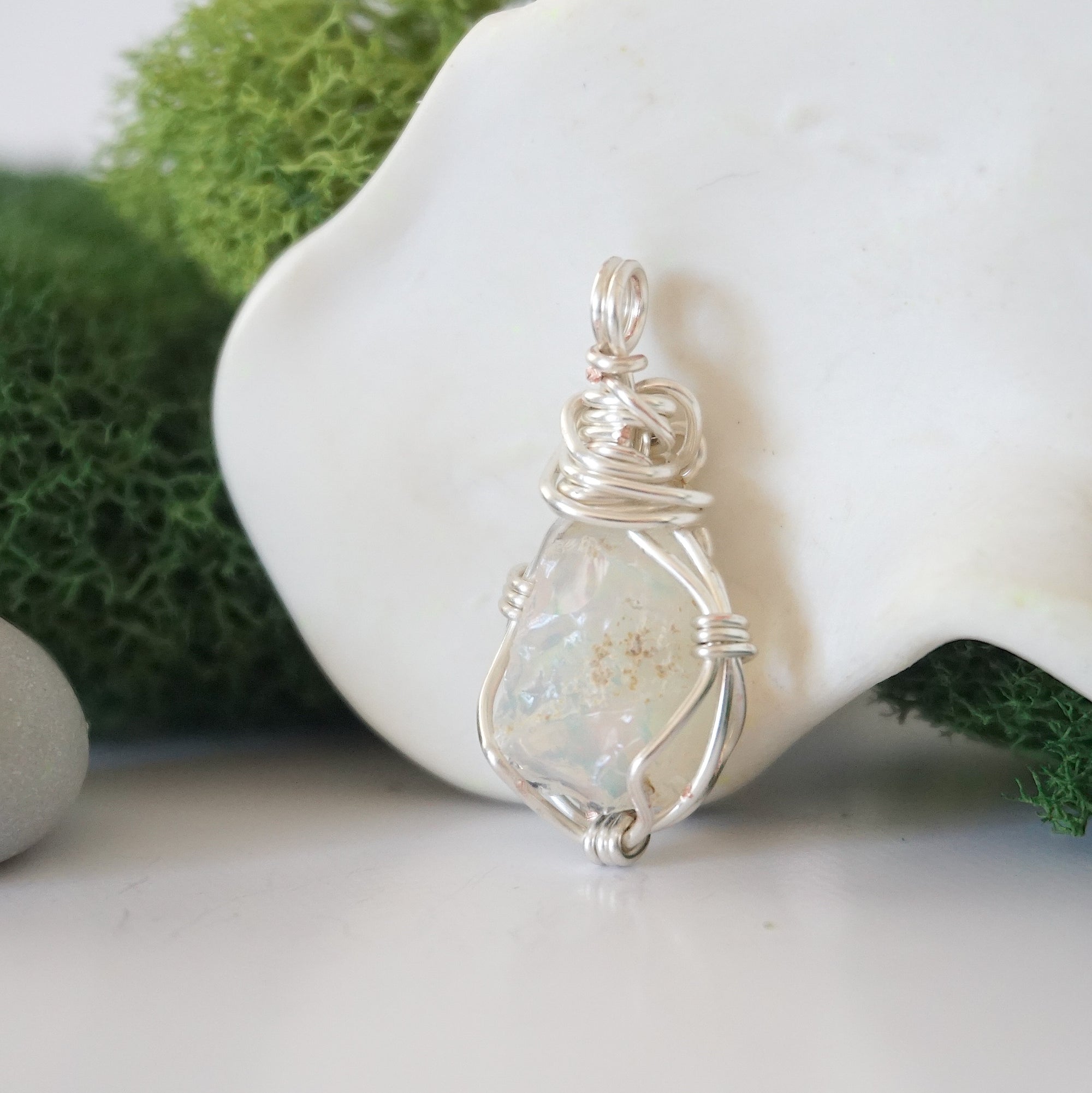 Detailed side angle view of simple raw opal pendant in silver wire