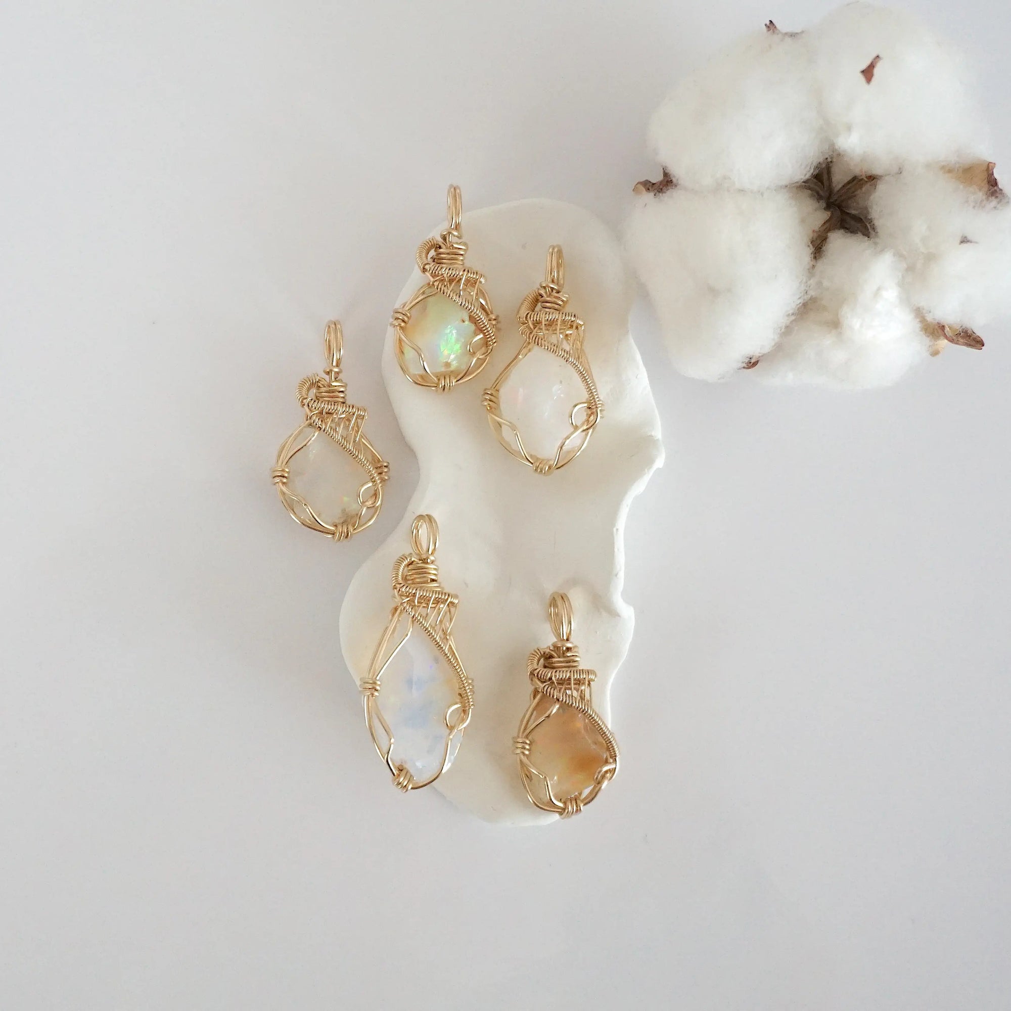 Five raw opal pendants in 14k gold filled, showing natural variation in size, shape, and color. Handcrafted October birthstone jewelry by Designs by Nature Gems.