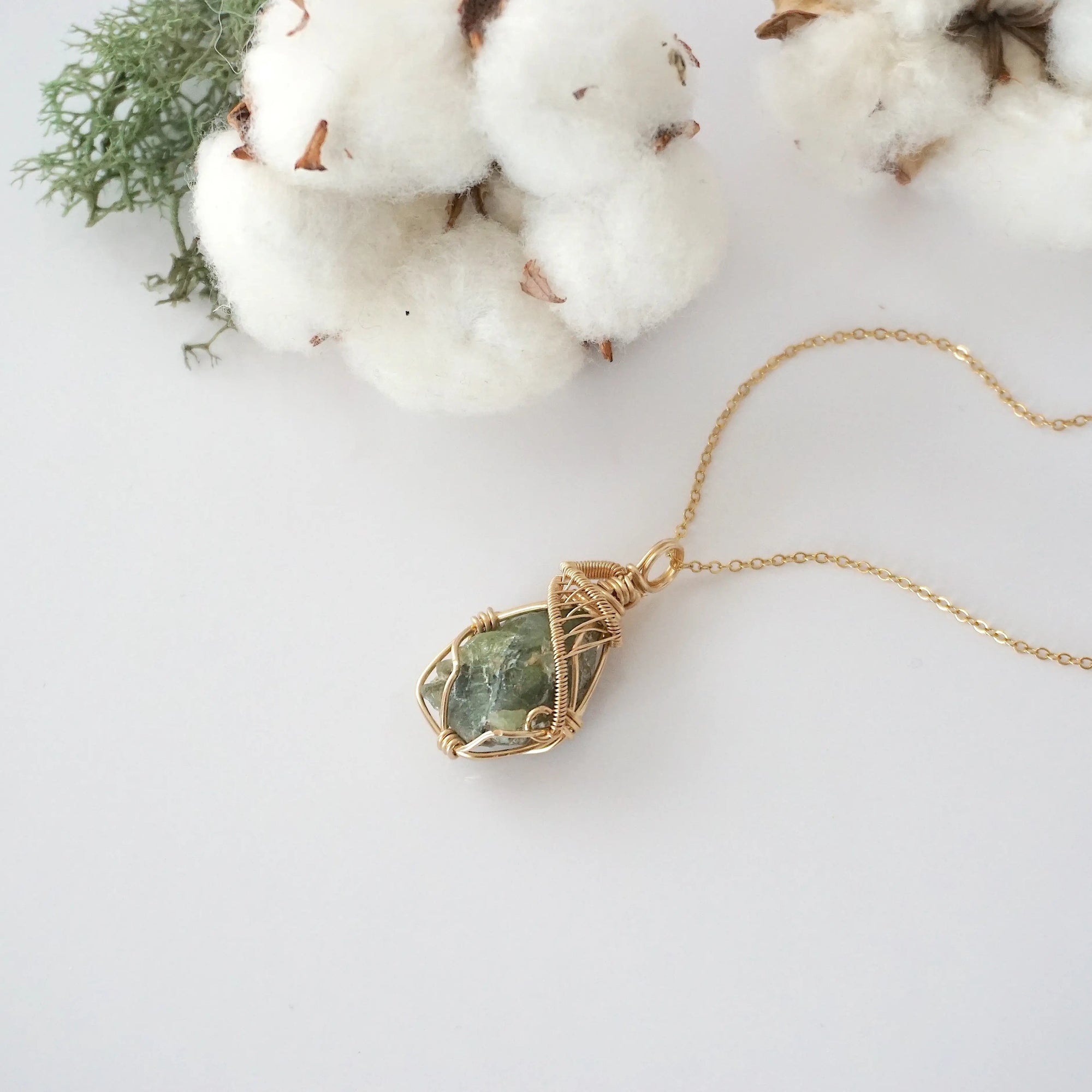 Raw peridot necklace in 14k gold filled laying flat. Handcrafted August birthstone jewelry for women by Designs by Nature Gems.