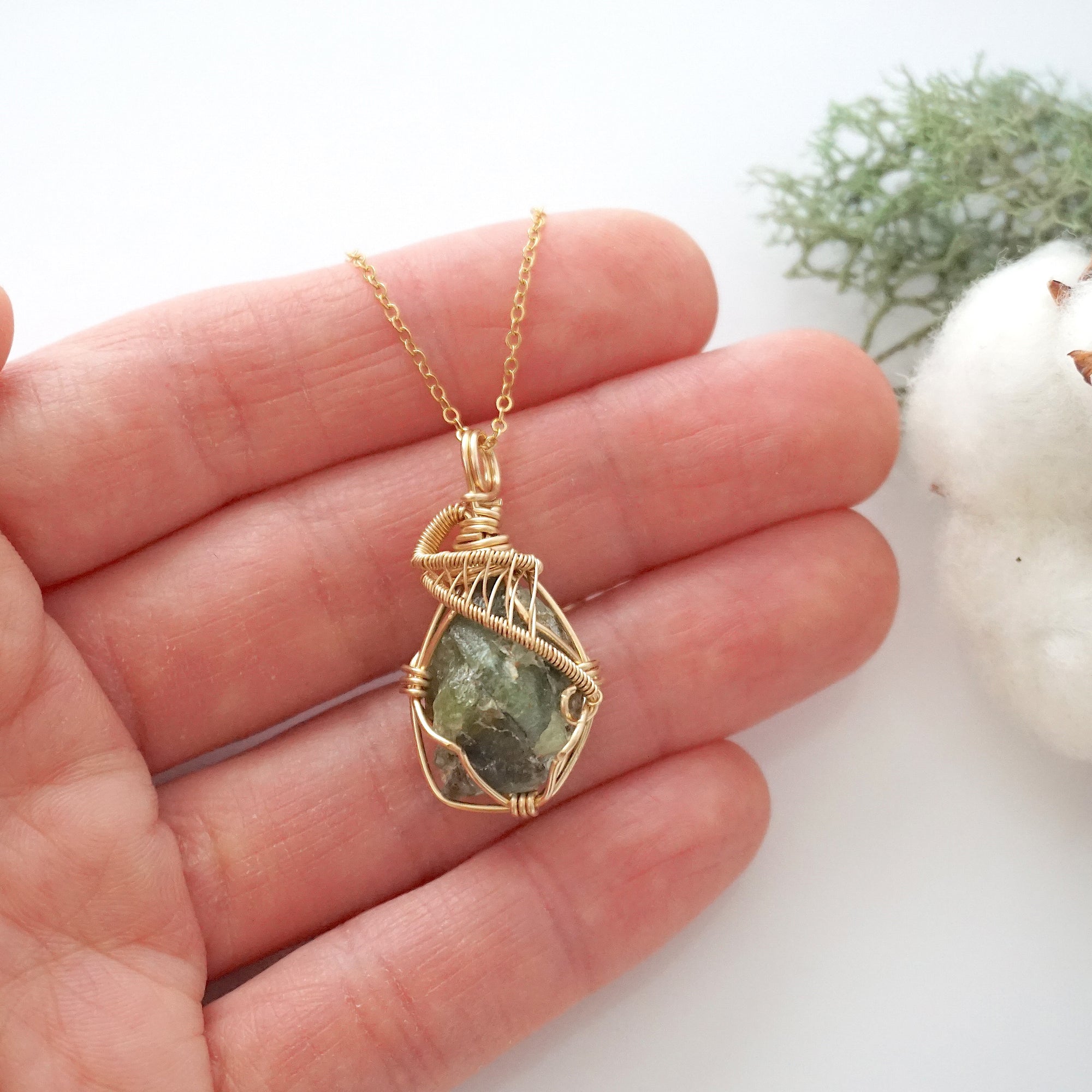 Raw peridot necklace in 14k gold filled shown in hand for size reference. Artisan August birthstone pendant by Designs by Nature Gems.