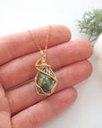 Raw peridot necklace in 14k gold filled shown in hand for size reference. Artisan August birthstone pendant by Designs by Nature Gems.