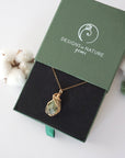Raw peridot necklace in 14k gold filled displayed in branded Designs by Nature Gems jewelry box. Artisan August birthstone gift for women.