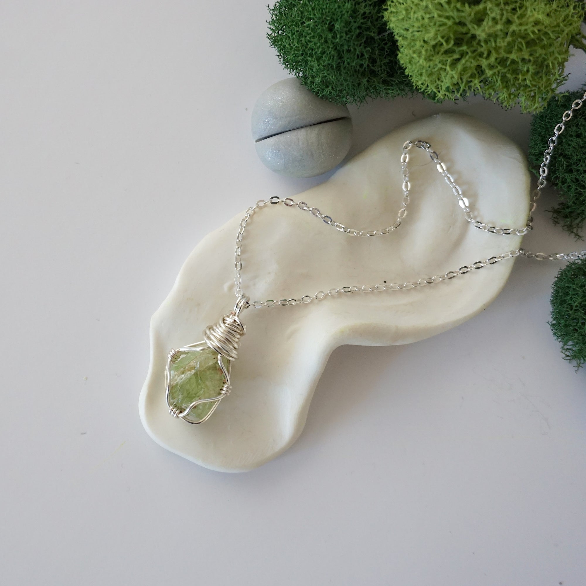 Simple raw peridot necklace with silver plated brass chain laying flat