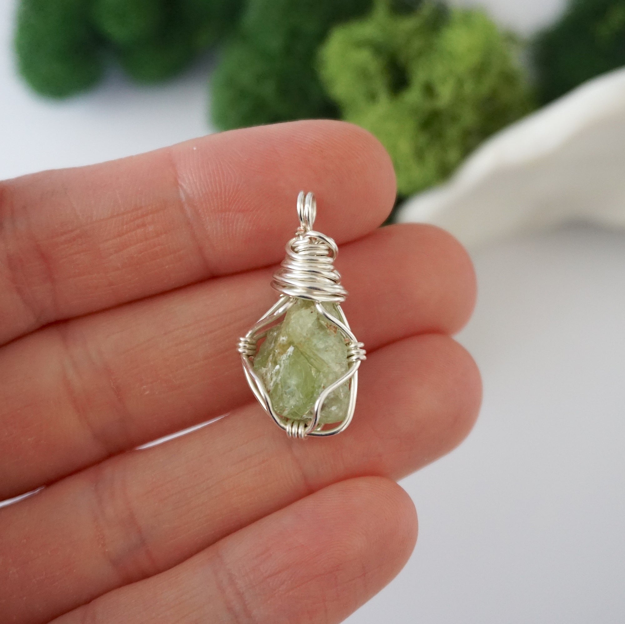 Simple raw peridot pendant shown in hand for size reference
