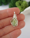 Simple raw peridot pendant shown in hand for size reference