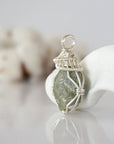 Left side detail of raw peridot crystal pendant — intricate silver finish wire weaving technique, nickel-free wire, handcrafted artisan wire wrapped jewelry, Designs by Nature Gems